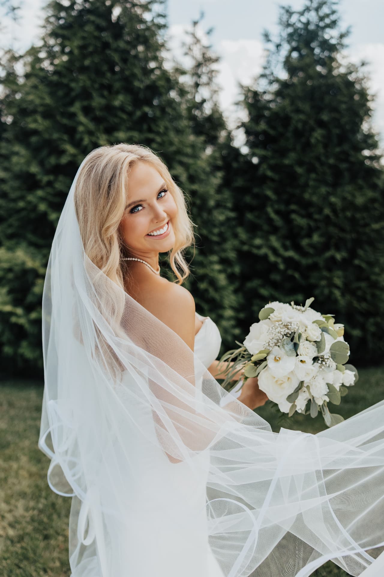 Bride glancing over her shoulder holding a white bouquet