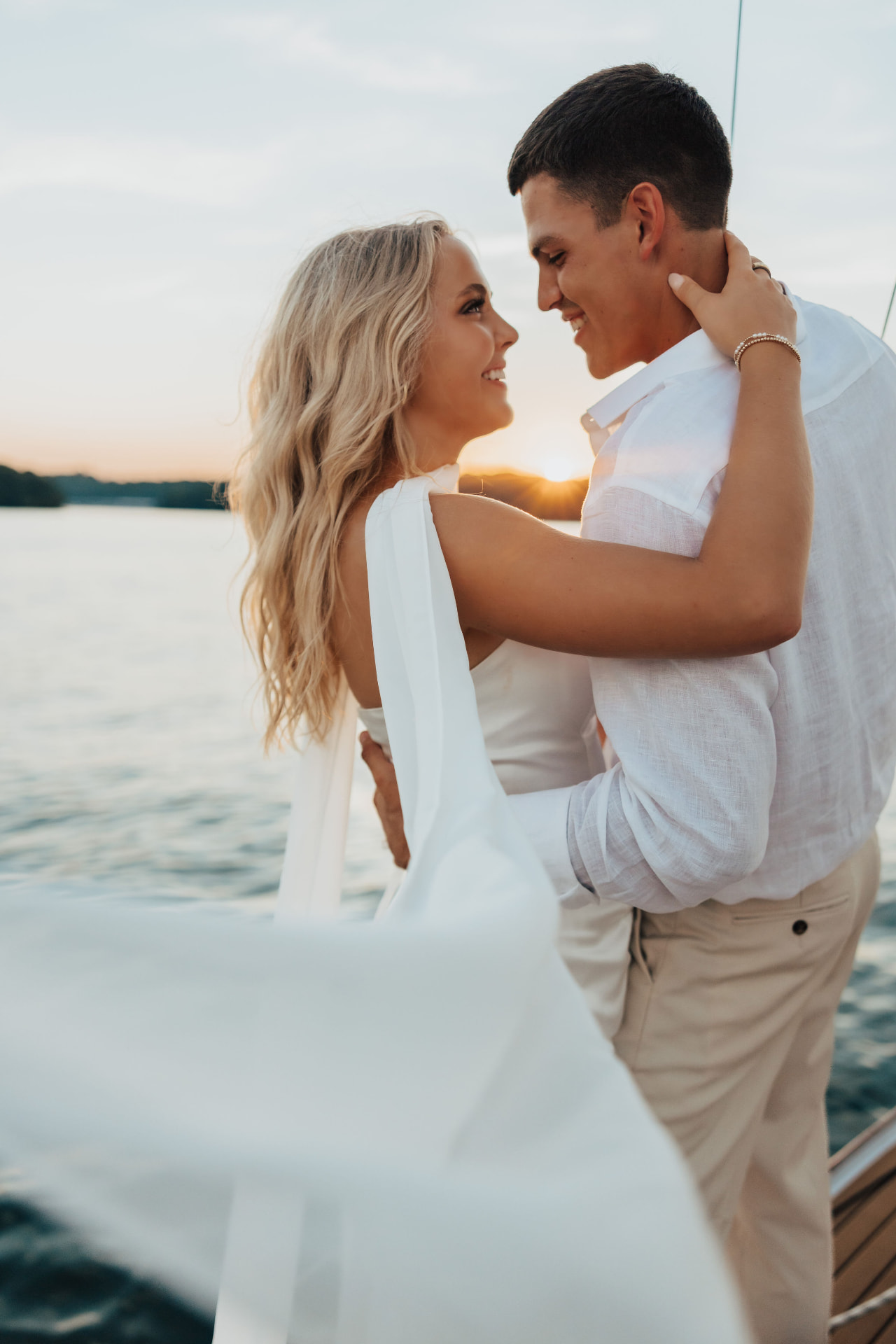 Couple laughing face to face on a sailboat at sunset
